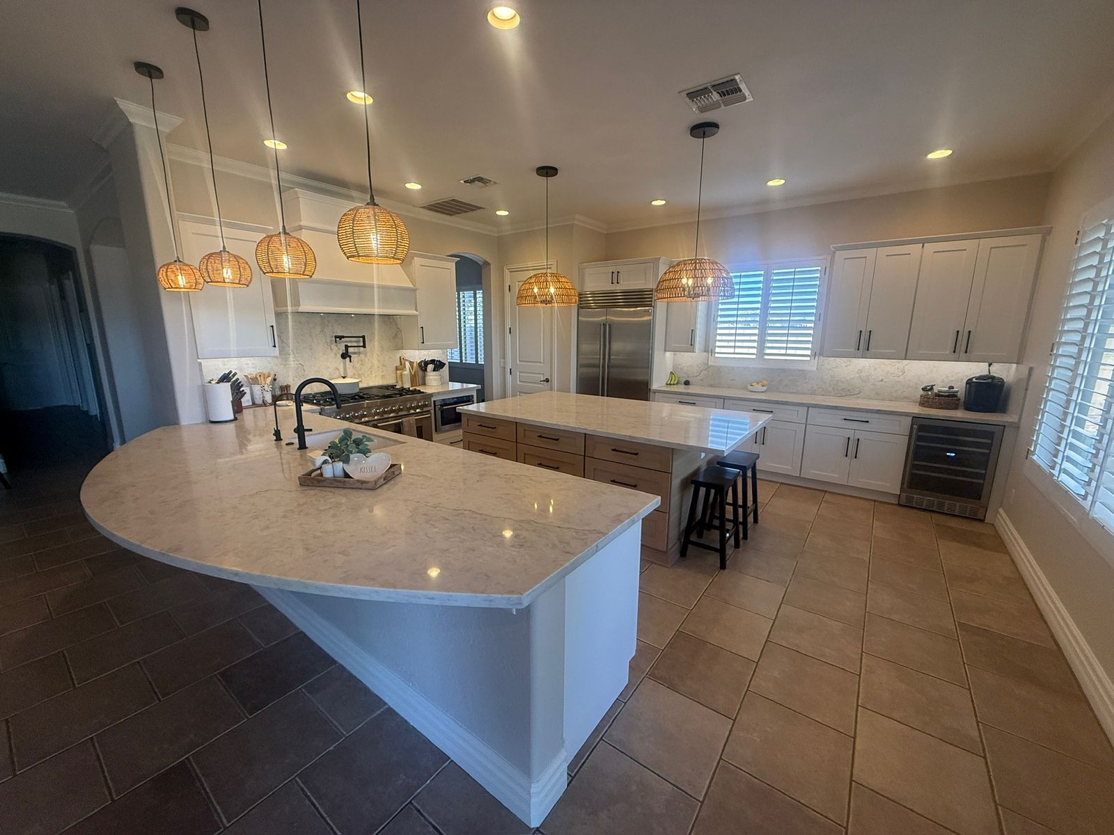 Stanley Brothers project: a wide kitchen with two islands, a custom hood over the range and woven pendant lighting