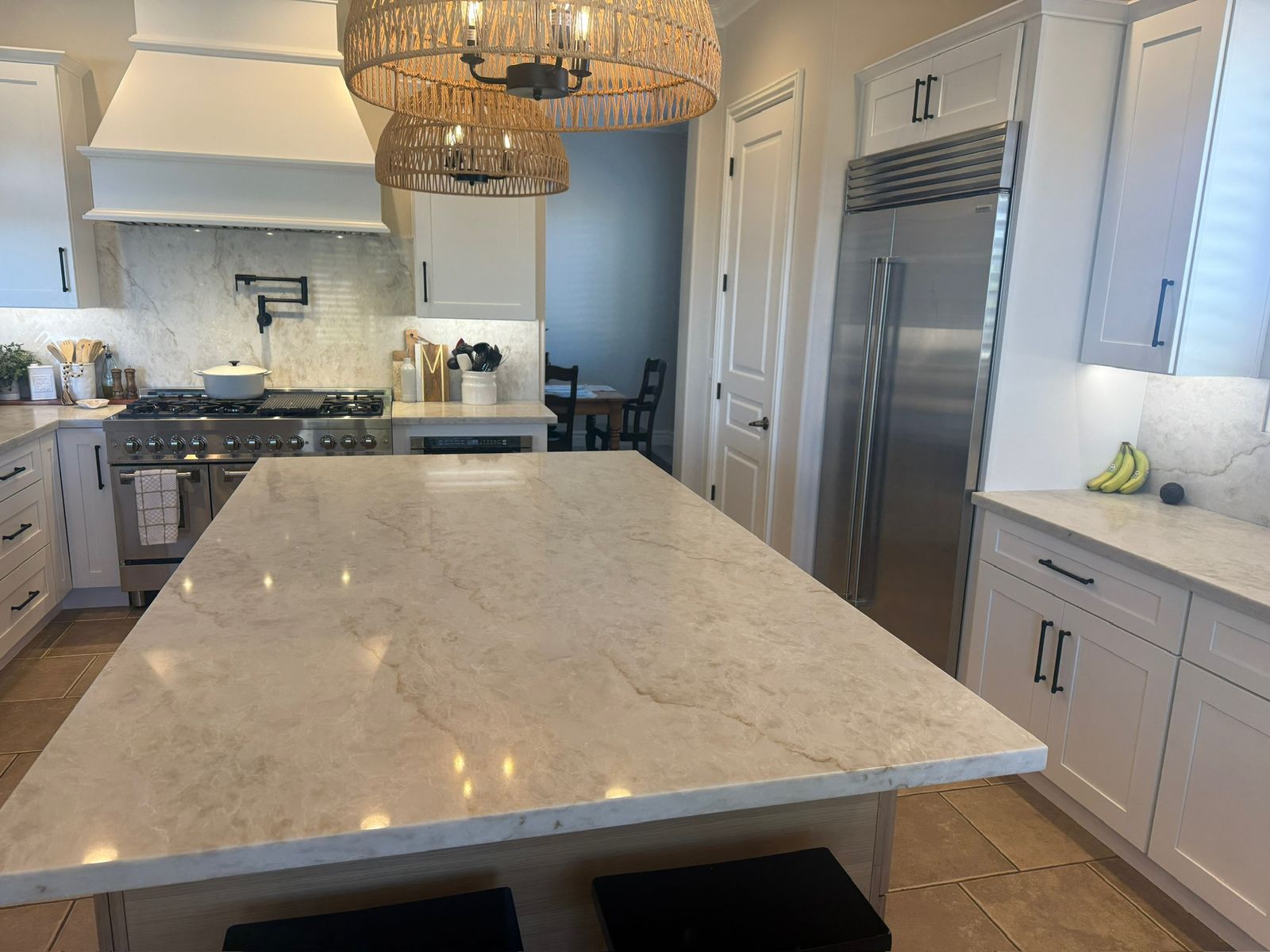 Stanley Brothers project: a kitchen island under woven pendants with a painted hood and a built-in refrigerator behind