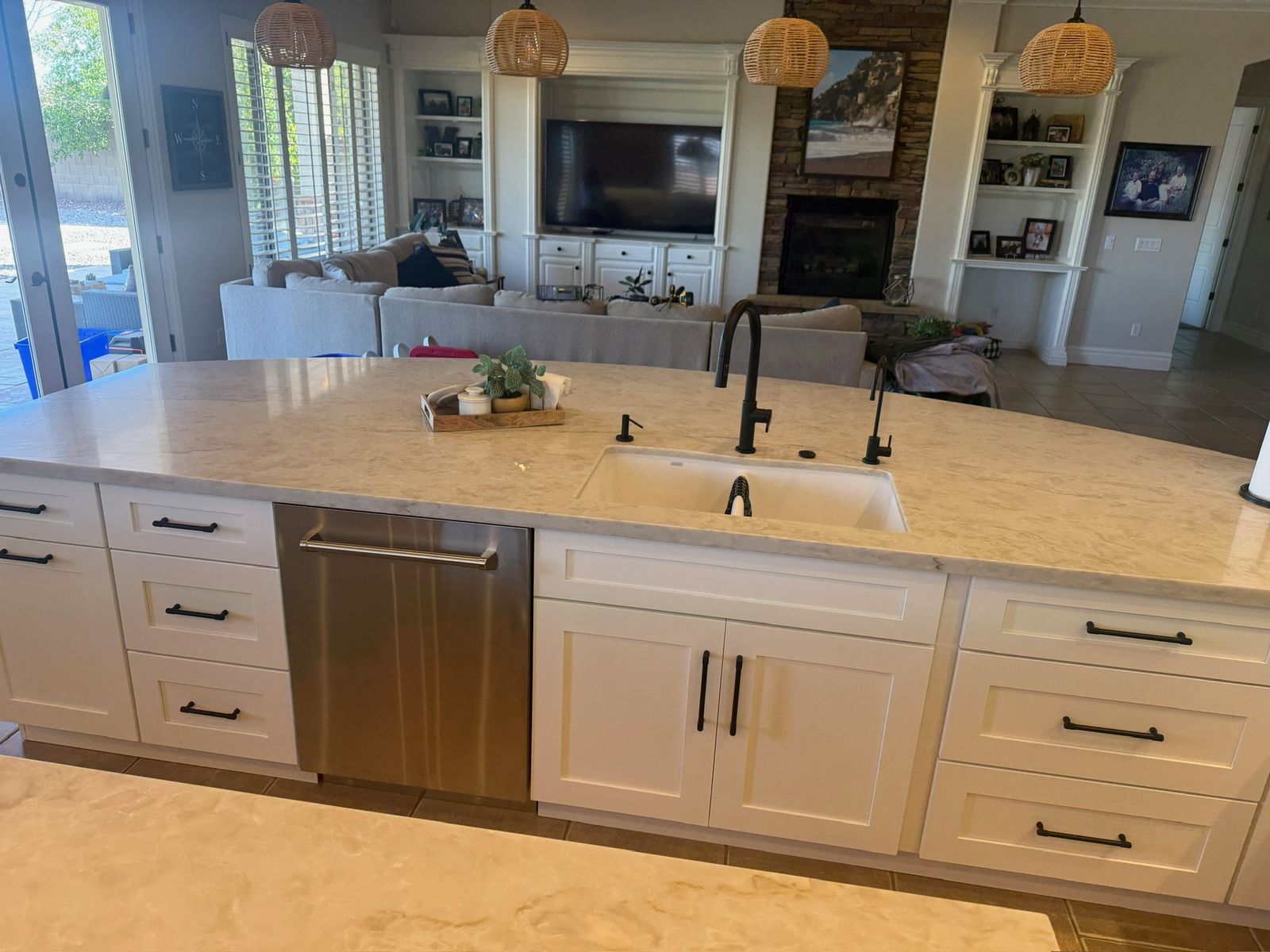Stanley Brothers project: a long stone island with an undermount sink, open to a great room
