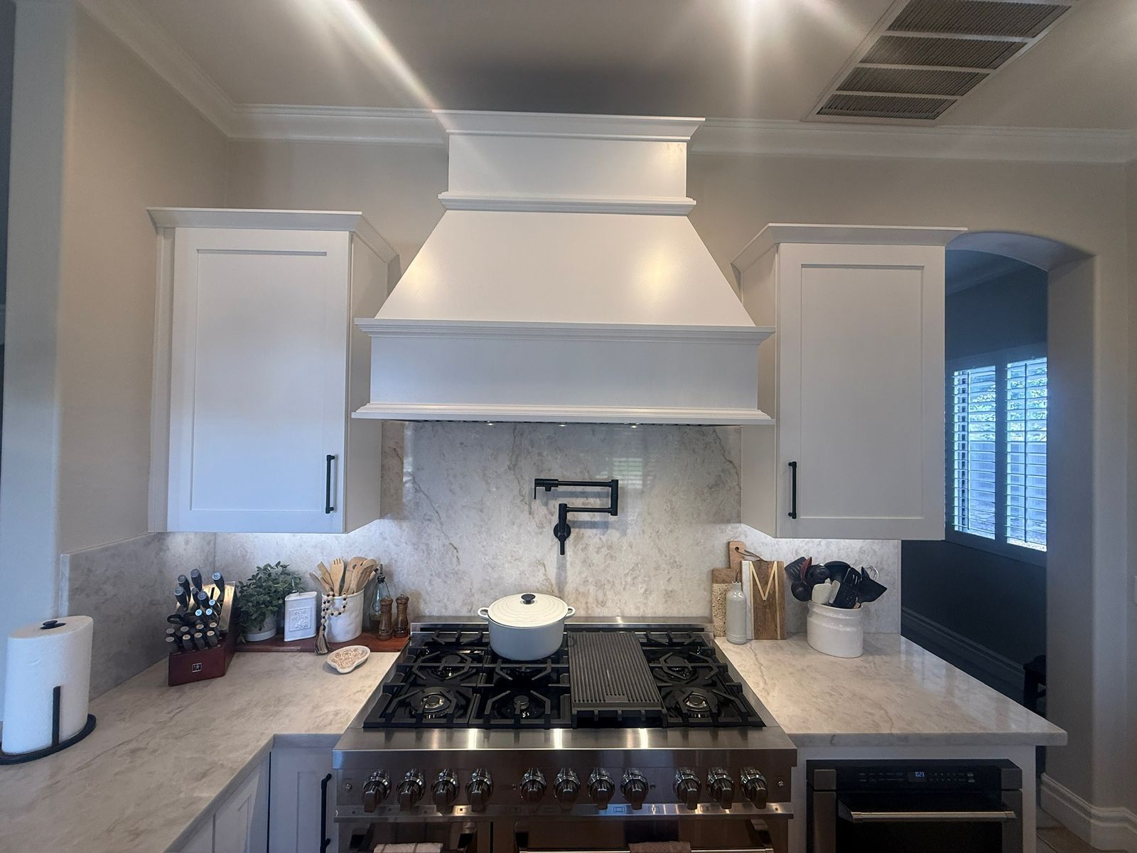 Stanley Brothers project: a professional range under a painted custom hood with a marble slab surround